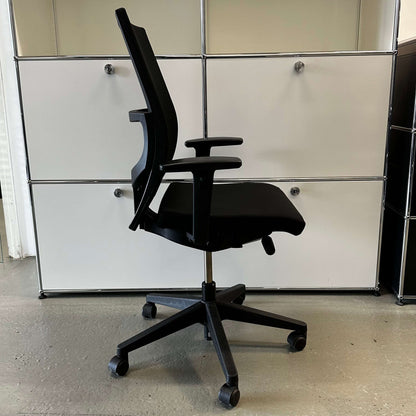 Haworth Comforto 39 black office chair with mesh back, adjustable armrests, height-adjustable seat, and black base with caster wheels