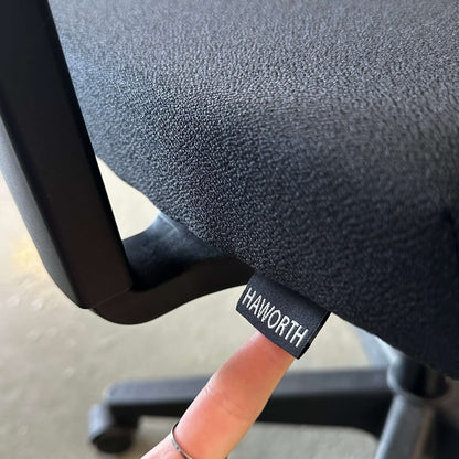 Close-up of black Haworth Comforto 39 office chair fabric with adjustable features and logo tag