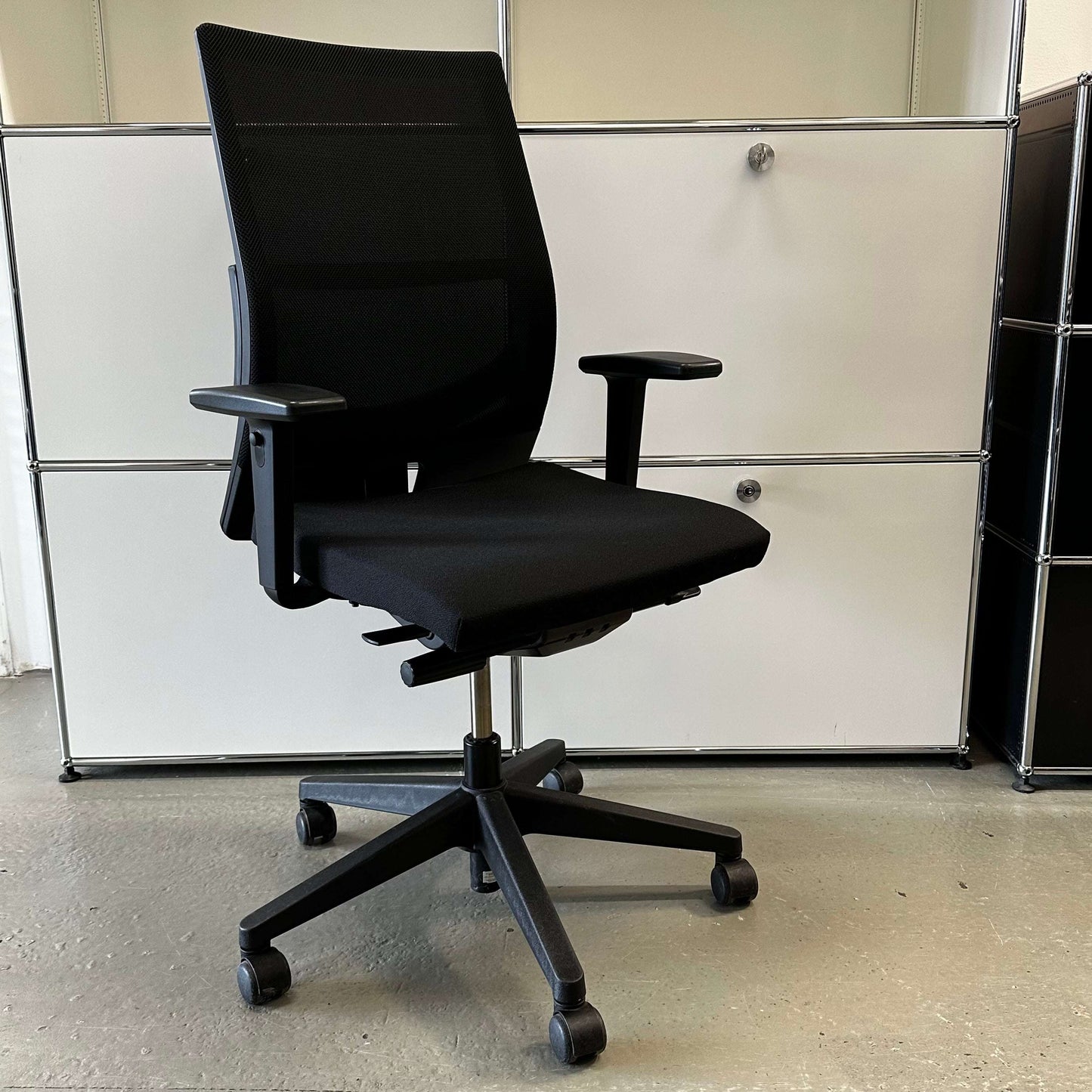 Black Haworth Comforto 39 office chair with mesh backrest, adjustable armrests, seat height, and black base with caster wheels