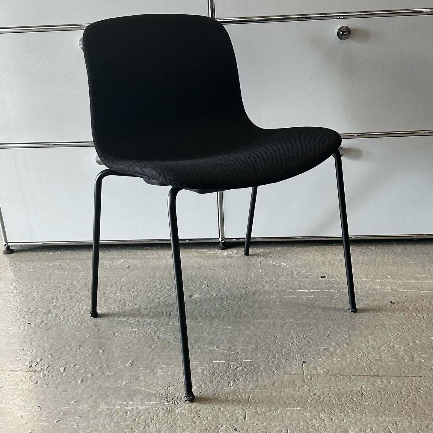 Modern black Hay Chair AAC 17 with sleek design and metal legs on concrete floor