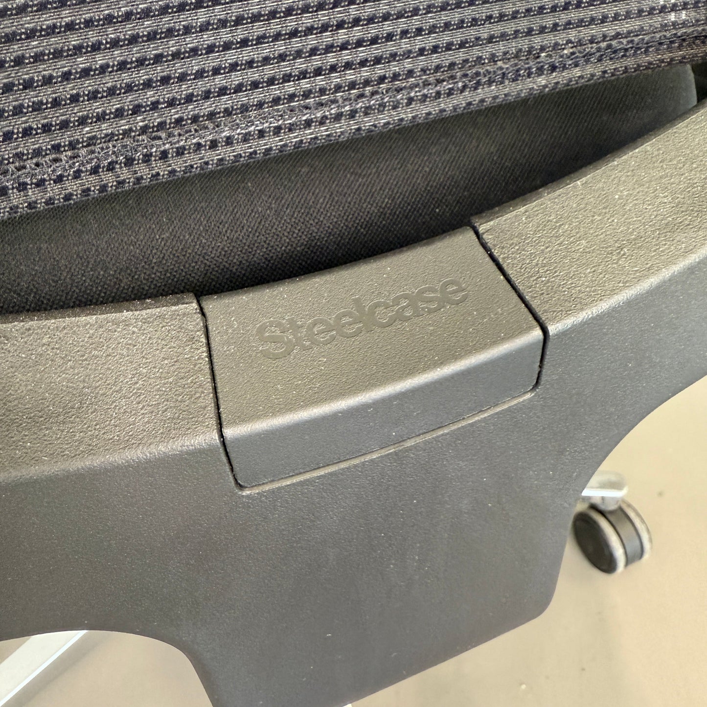 Nahaufnahme des schwarzen Steelcase Reply Bürostuhls mit Stoffbezug und Mesh-Rückenlehne, verstellbaren Armlehnen und Chrom-Fußkreuz.