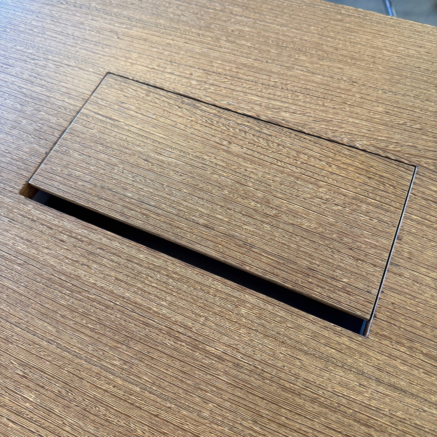 Nahaufnahme eines Kabelablagefachs in der Tischplatte des Spiegels .con air Schreibtischs mit Holzstruktur