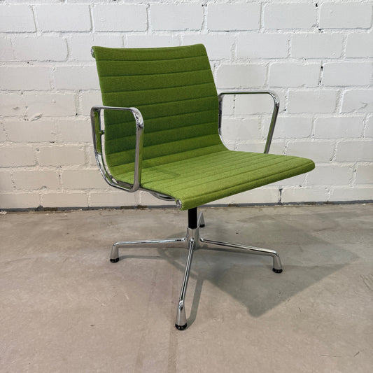 Vitra EA 108 Hopsak swivel chair in green fabric with chrome frame against white brick wall