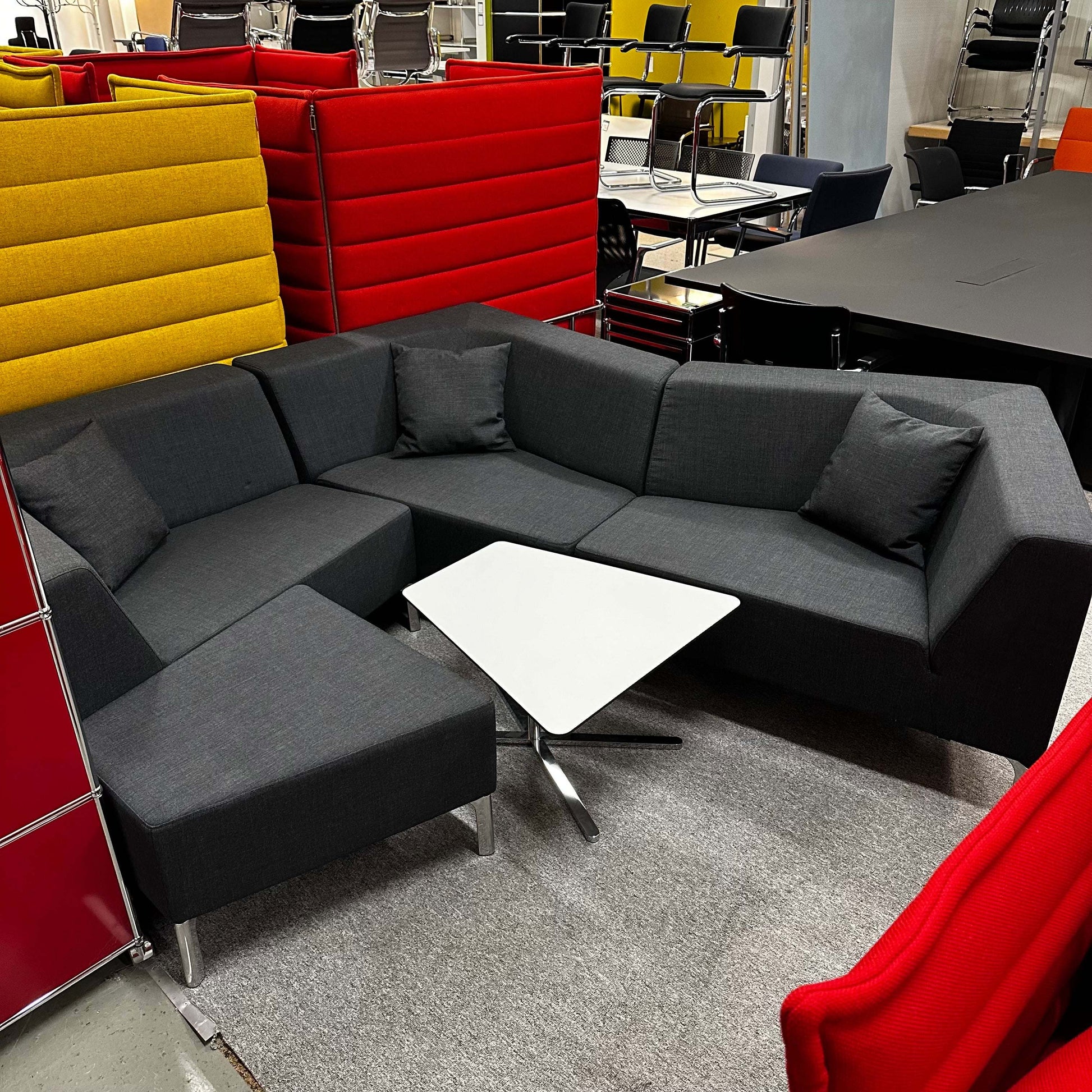 Interstuhl Sitzgruppe Tangram dark gray modular sectional sofa with white triangular table in office setting