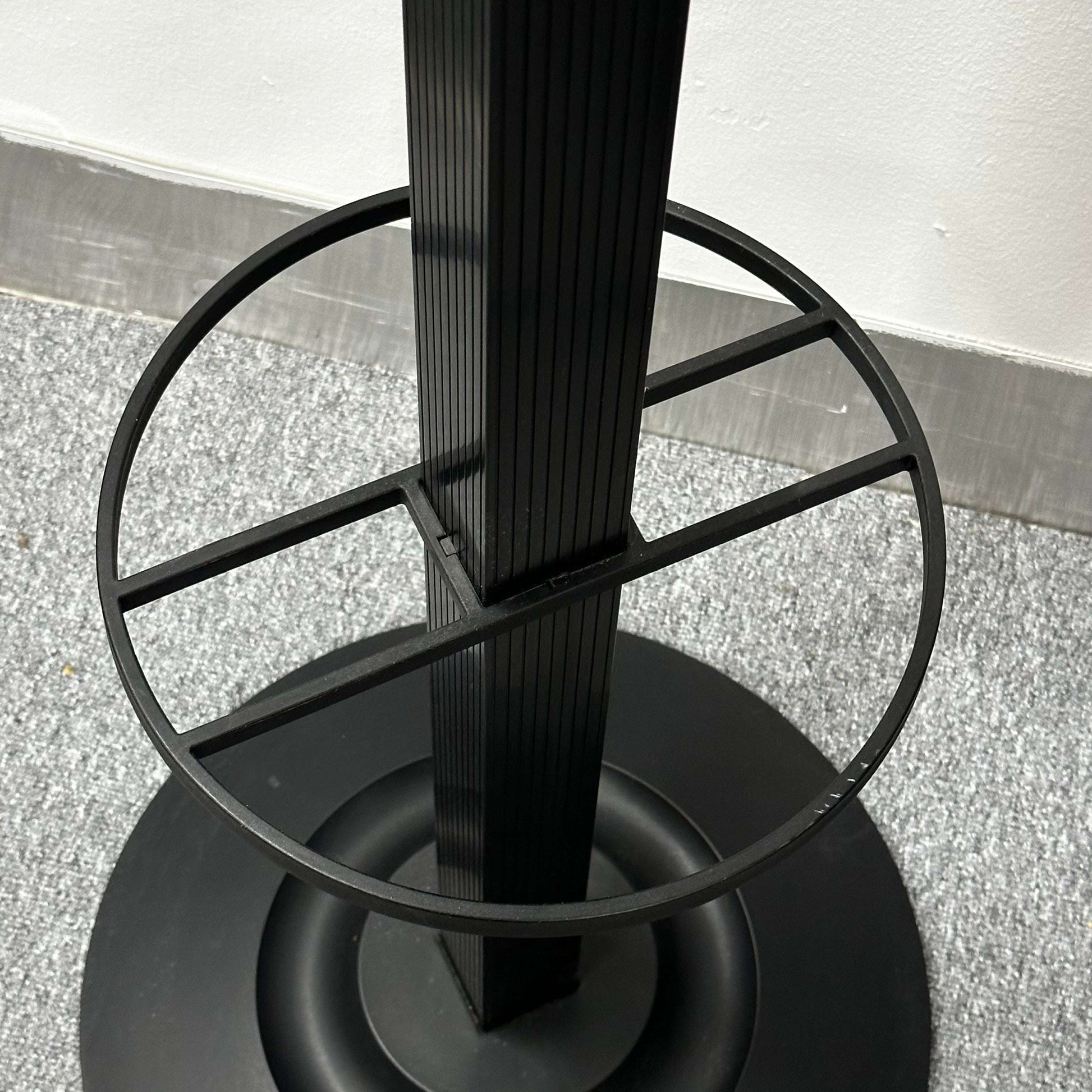 Close-up of the black Kartell Segmenti Garderobenständer base and ring detail on a carpeted floor
