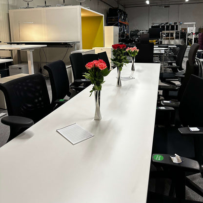 white and silver 4 meter long Konferenztisch 4m x 80 cm with black chairs and decorative flower vases in modern office setting