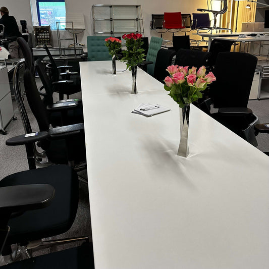 White and silver 4 meter long konferenztisch 4m x 80 cm with vases of pink roses and black office chairs