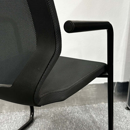 Close-up of black König+Neurath Konferenzstuhl with mesh seat and armrest in modern office setting