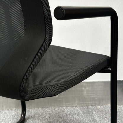 Close-up of König+Neurath Konferenzstuhl with black mesh seat and armrest in modern office setting