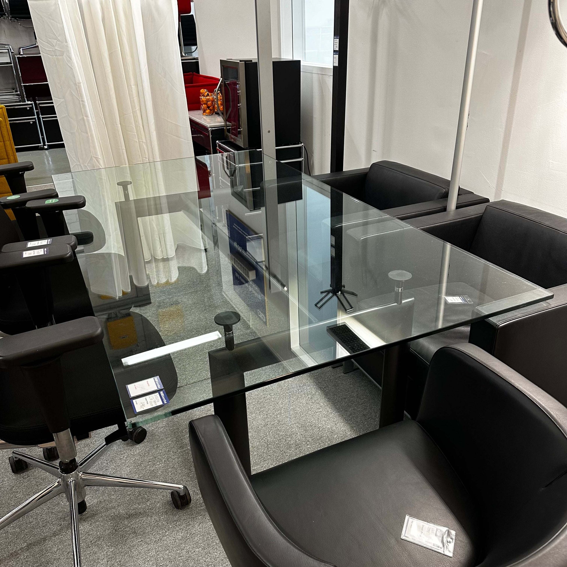 Adjustable height LC6 Tisch replica with glass tabletop and black chairs around in office setting