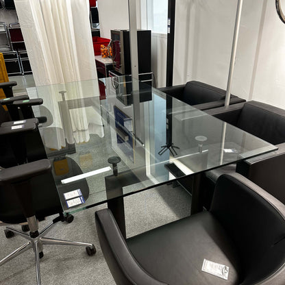 Adjustable height LC6 Tisch replica with glass tabletop and black chairs around in office setting
