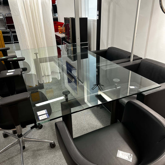 Adjustable height LC6 Tisch replica with glass tabletop and black chairs around in office setting