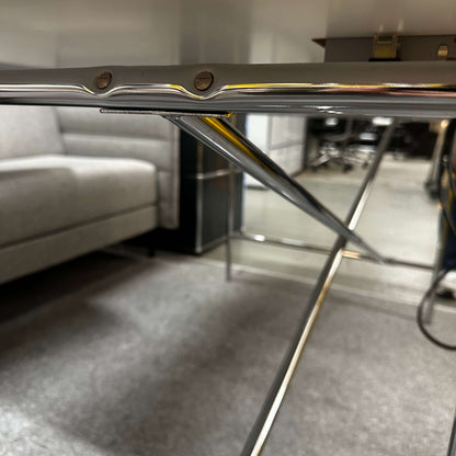 Close-up of the chrome crossed side frame of the Lampert Eiermann Tisch with a white tabletop in a modern room setting