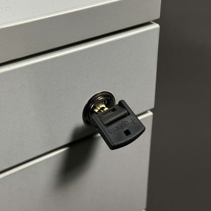 Nahaufnahme eines weißen, abschließbaren Ophelis Rollcontainers aus Holz mit Schlüssel im Schließzylinder