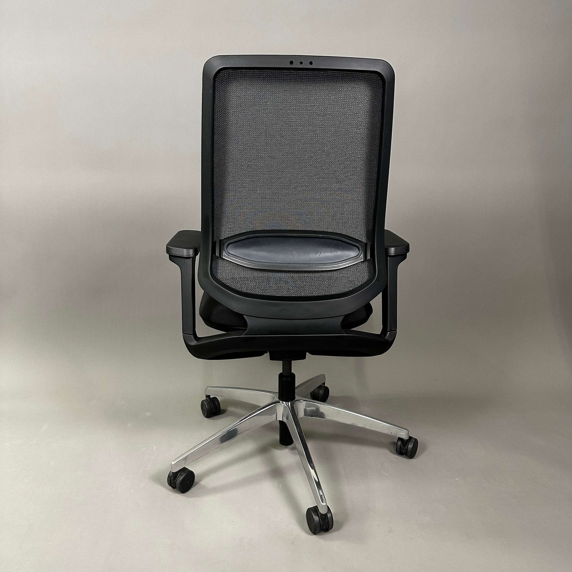 Back view of black SEDUS se:flex ergonomic office chair with mesh back, adjustable armrests, and swivel base with rubberized hard floor casters