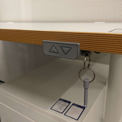 Close-up of electric height adjustment control on Ikea Bekant white 160x80cm desk with multiplex edge and keychain accessory.
