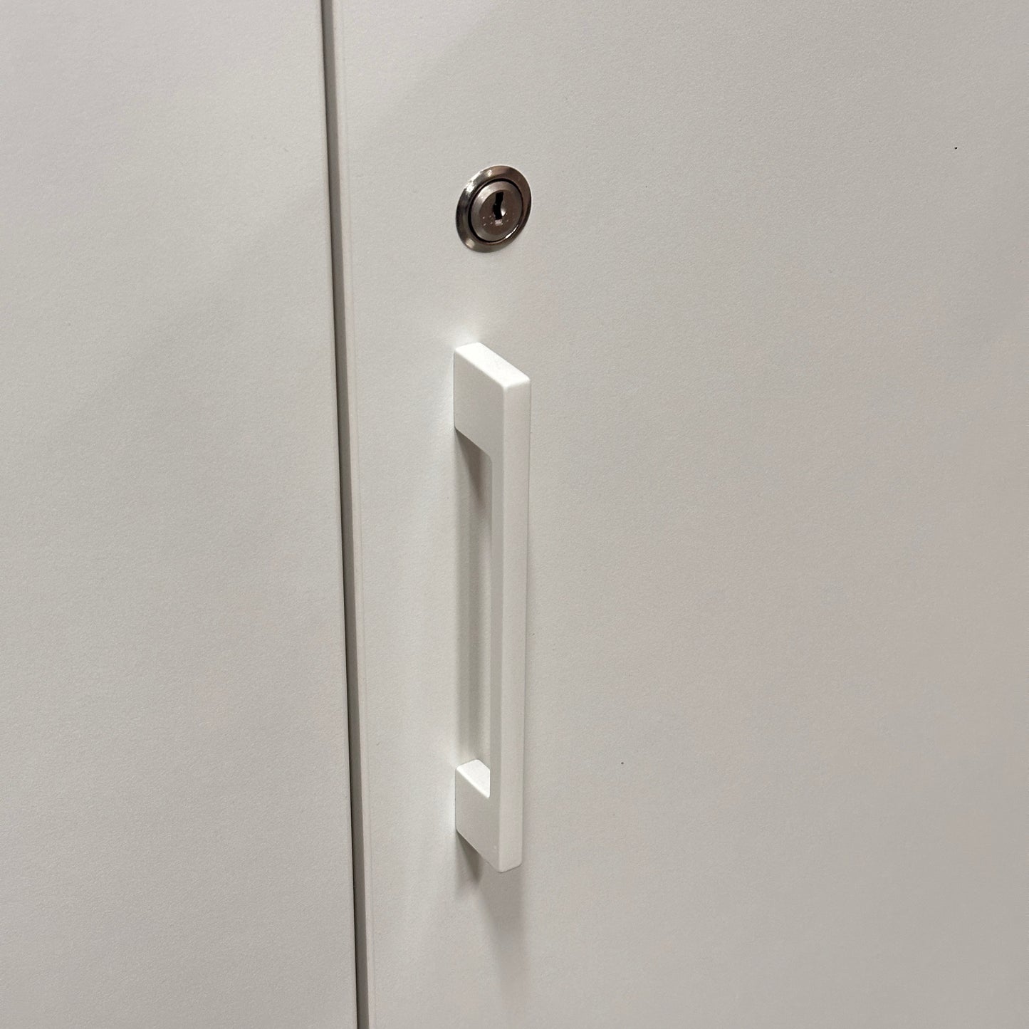 Weißer Sedus Flügeltürenschrank mit modernem Griff und silbernem Schloss.
