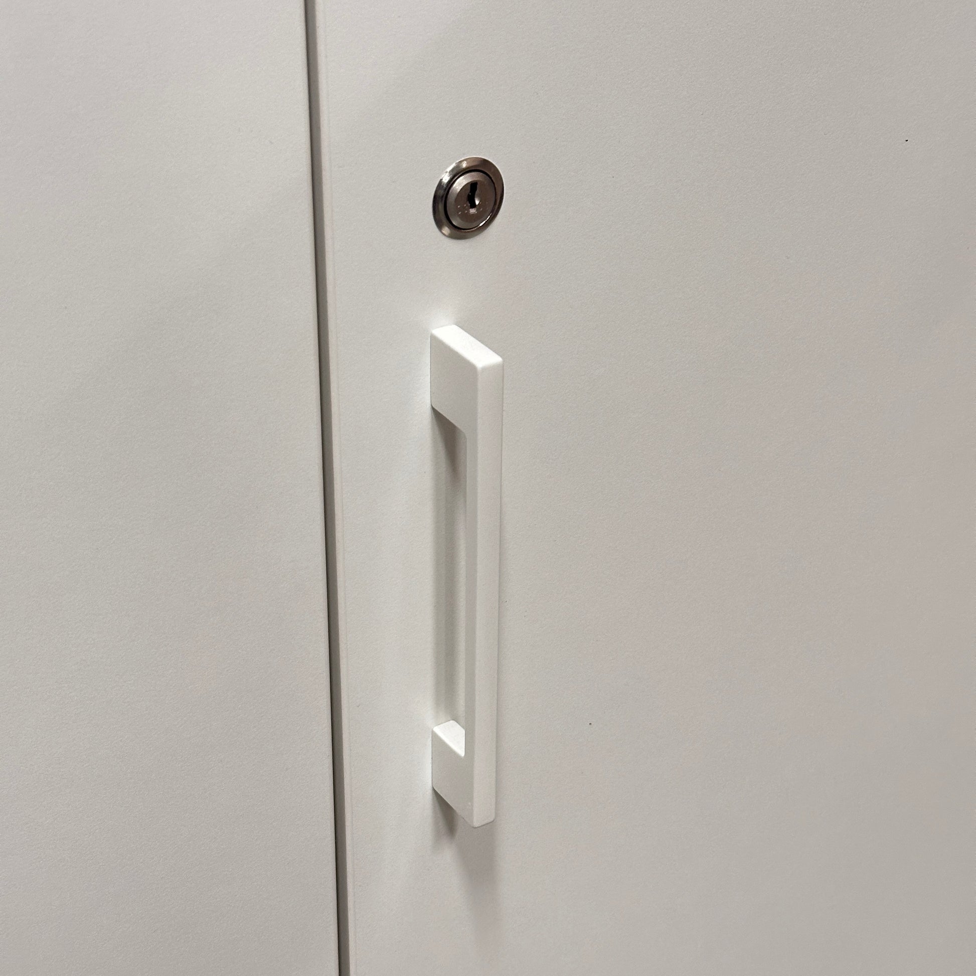 Weißer Sedus Flügeltürenschrank mit modernem Griff und silbernem Schloss.