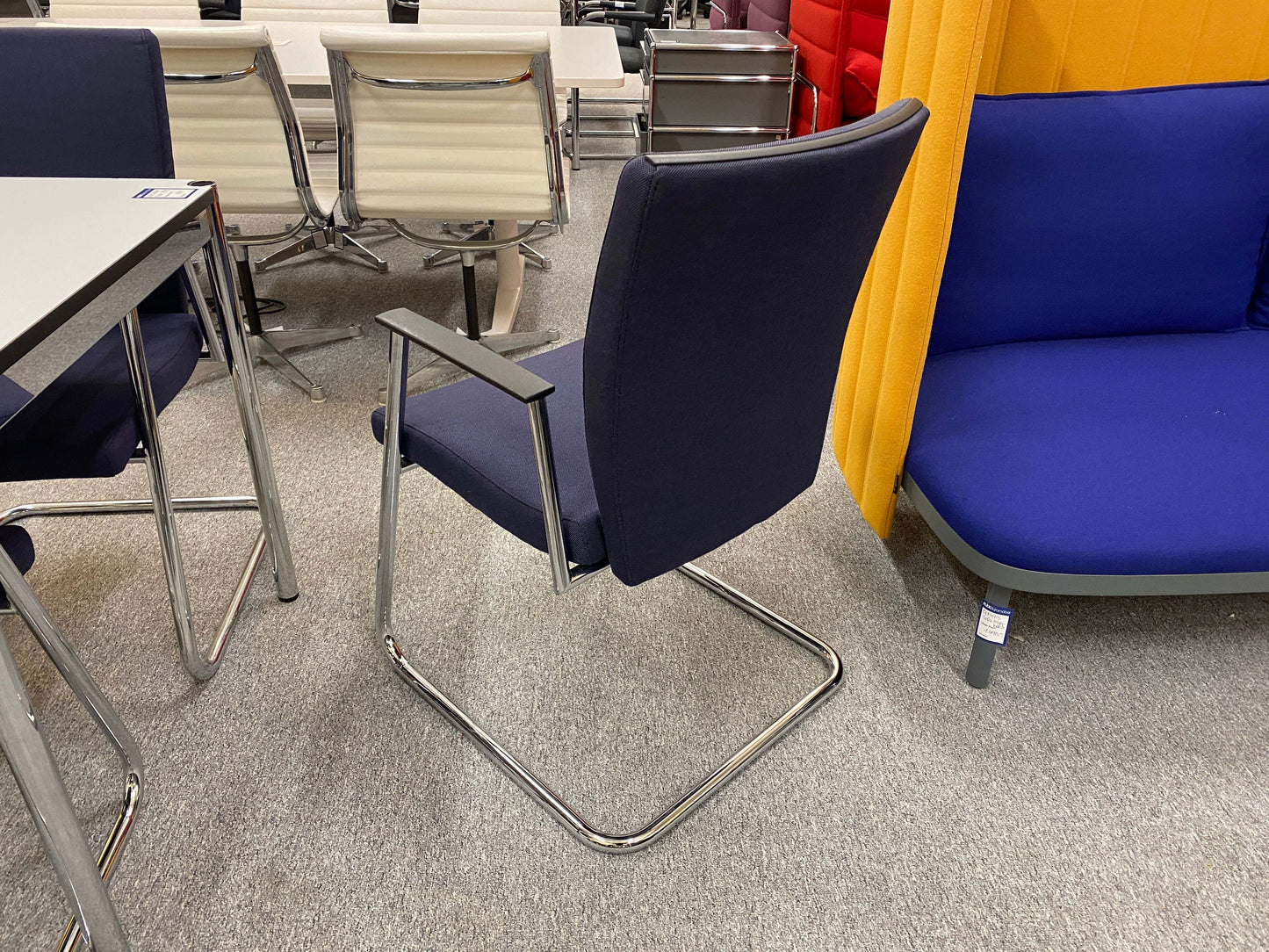 Sedus Freischwinger office chair with navy fabric seat and chrome cantilever frame in modern workspace setting