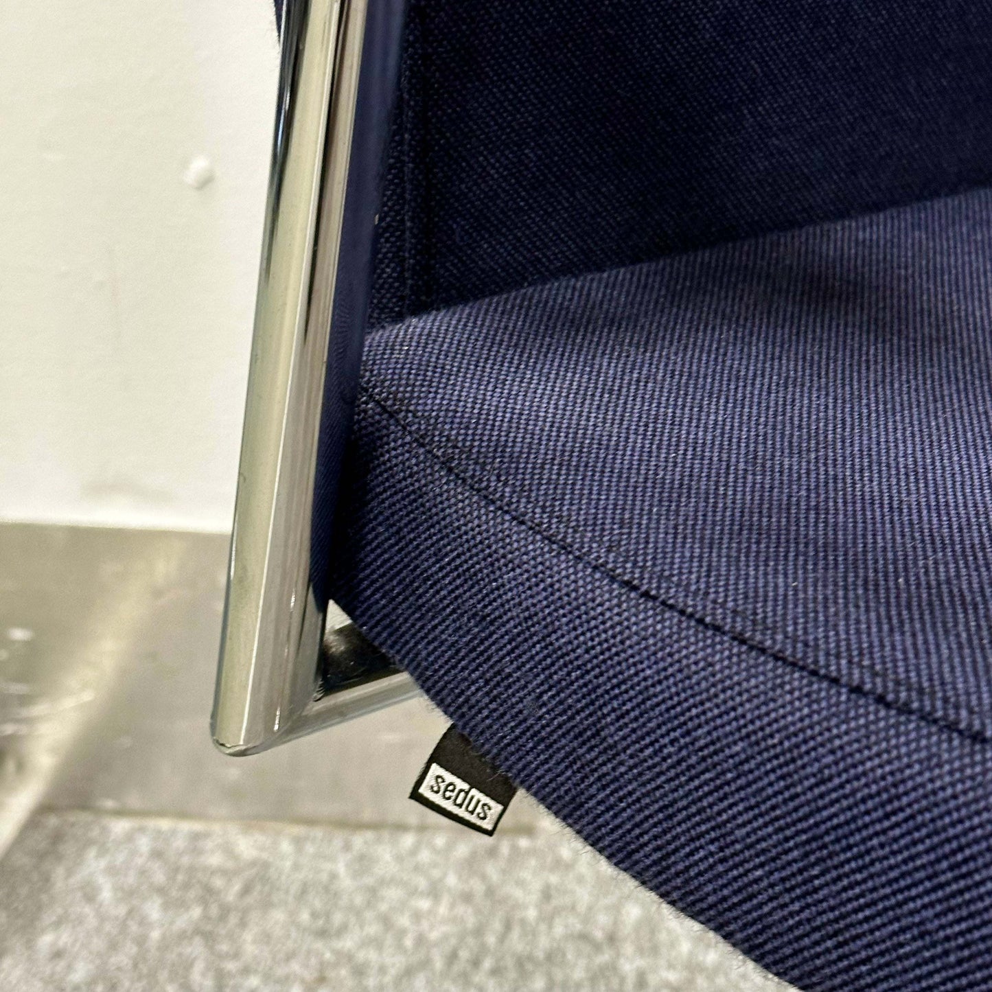 Close-up of navy blue fabric seat and chrome frame of Sedus Freischwinger ergonomic office chair