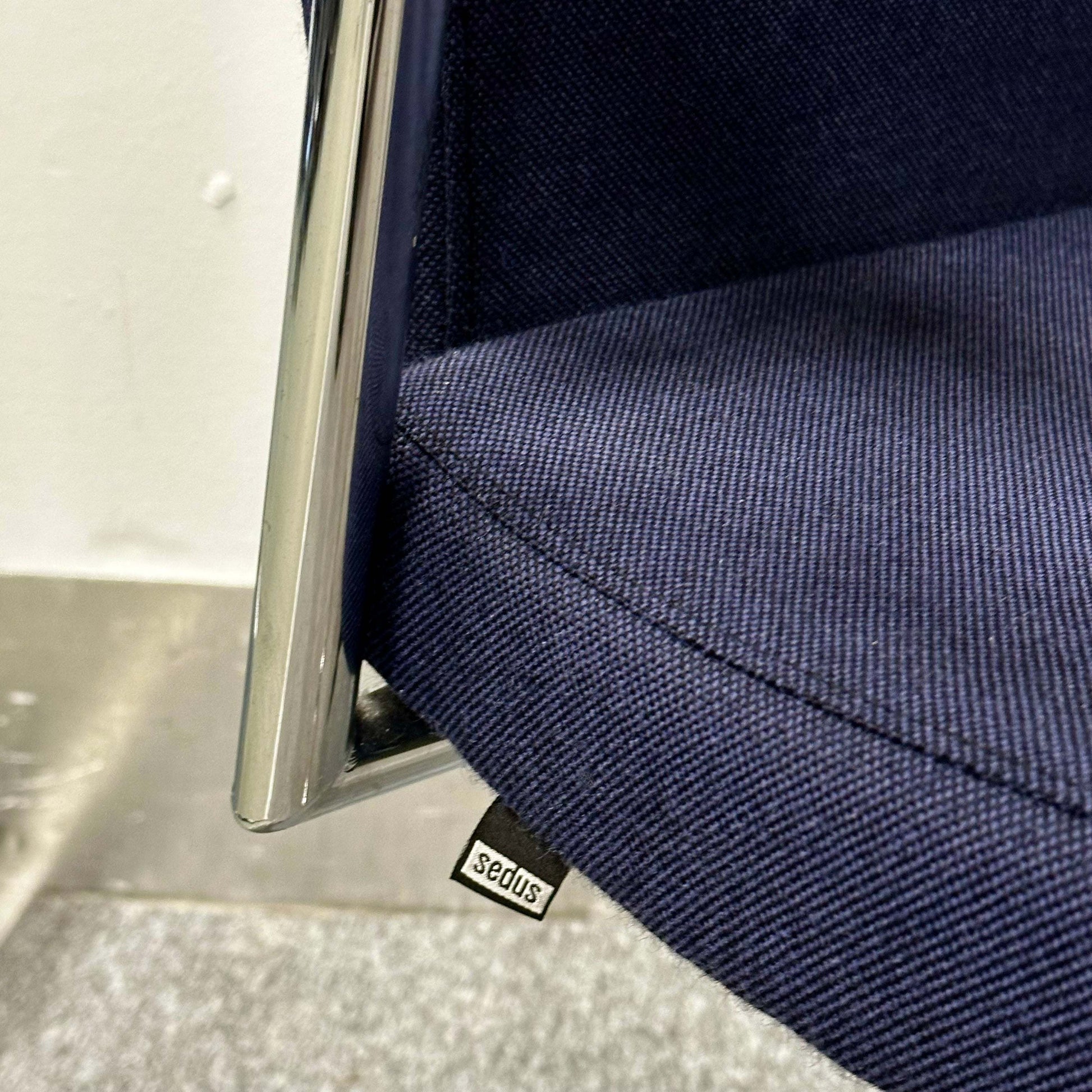 Close-up of navy blue fabric seat and chrome frame of Sedus Freischwinger ergonomic office chair