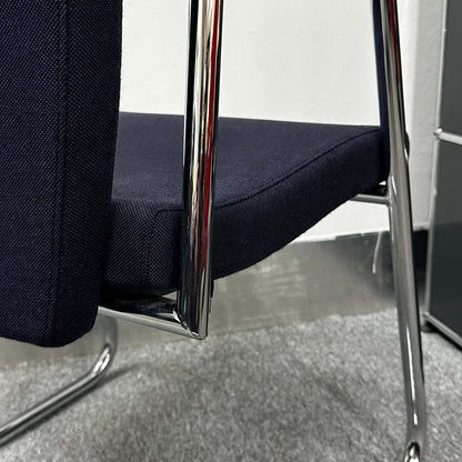 Close-up of Sedus Freischwinger chair with navy fabric seat and chrome cantilever frame on carpeted floor