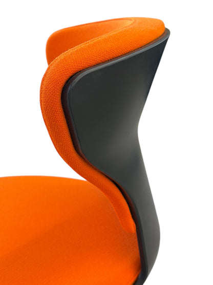 Close-up of an orange fabric Sedus Turn Around 181 high desk chair with a black polypropylene back.