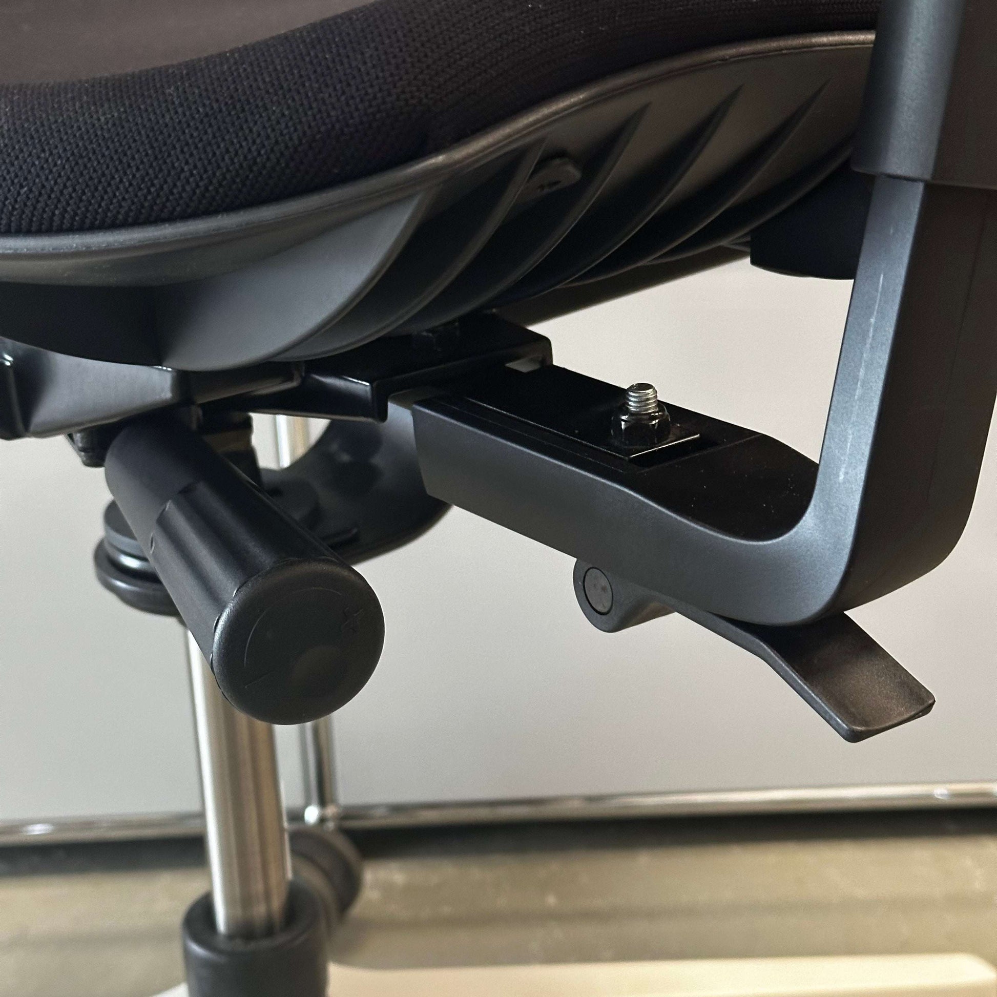 Close-up of Sitag Wave black upholstered office chair with white frame, height-adjustable seat, depth suspension, 3D armrests with soft pads, and adjustable backrest angle and height.