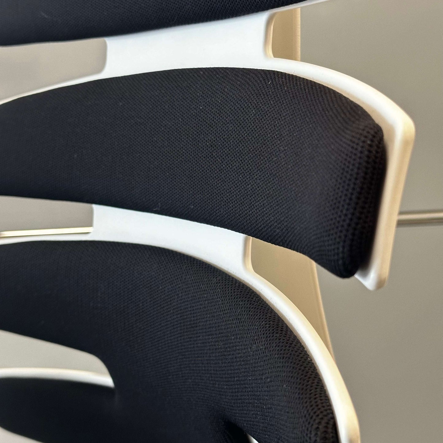 Close-up of black upholstered Sitag Wave chair backrest with white frame and ergonomic design features