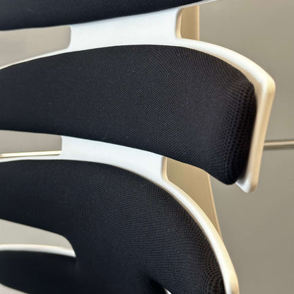 Close-up of black upholstered Sitag Wave chair backrest with white frame and ergonomic design features