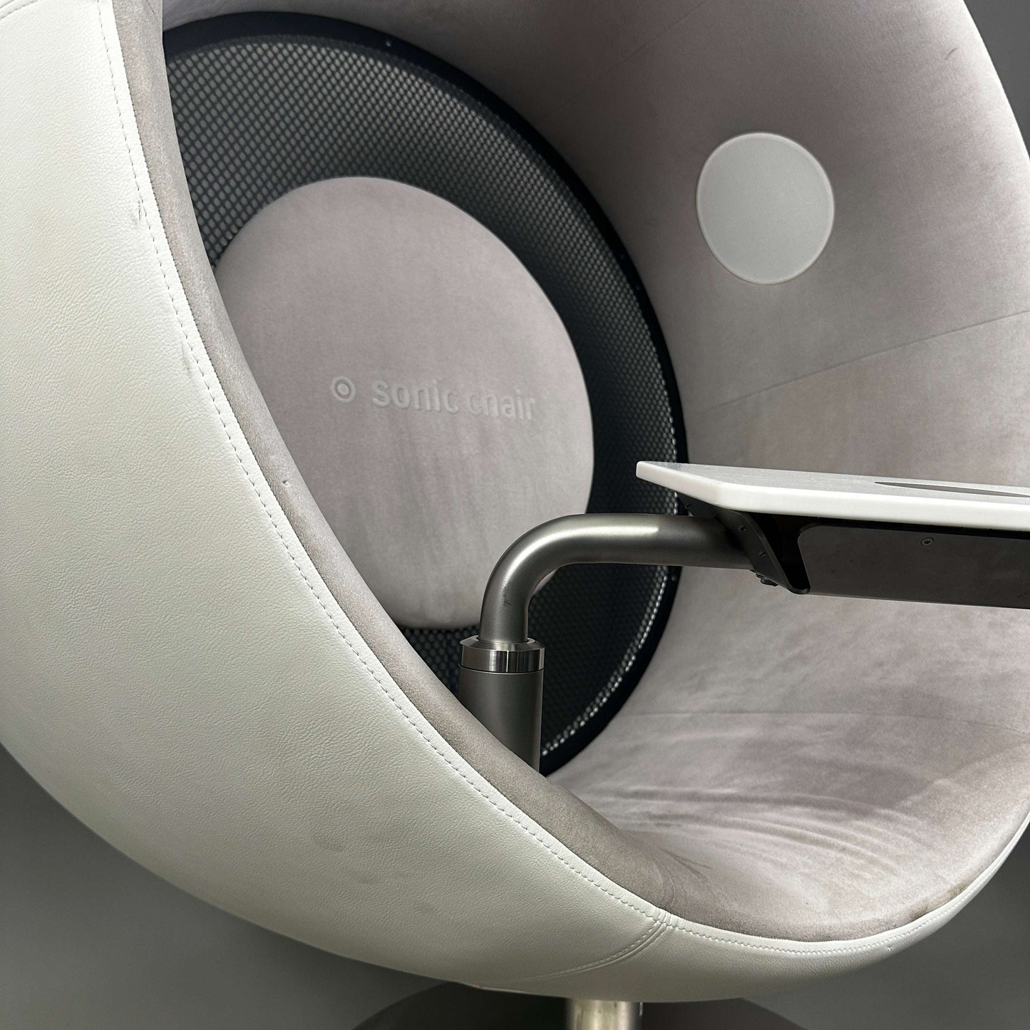 Sonic Chair 3.1 Audiosessel aus weißem Glattleder mit hellgrauem Veloursleder, integrierter Laptoptisch und hochwertiger Körperschallmembran für intensives Klangerlebnis.