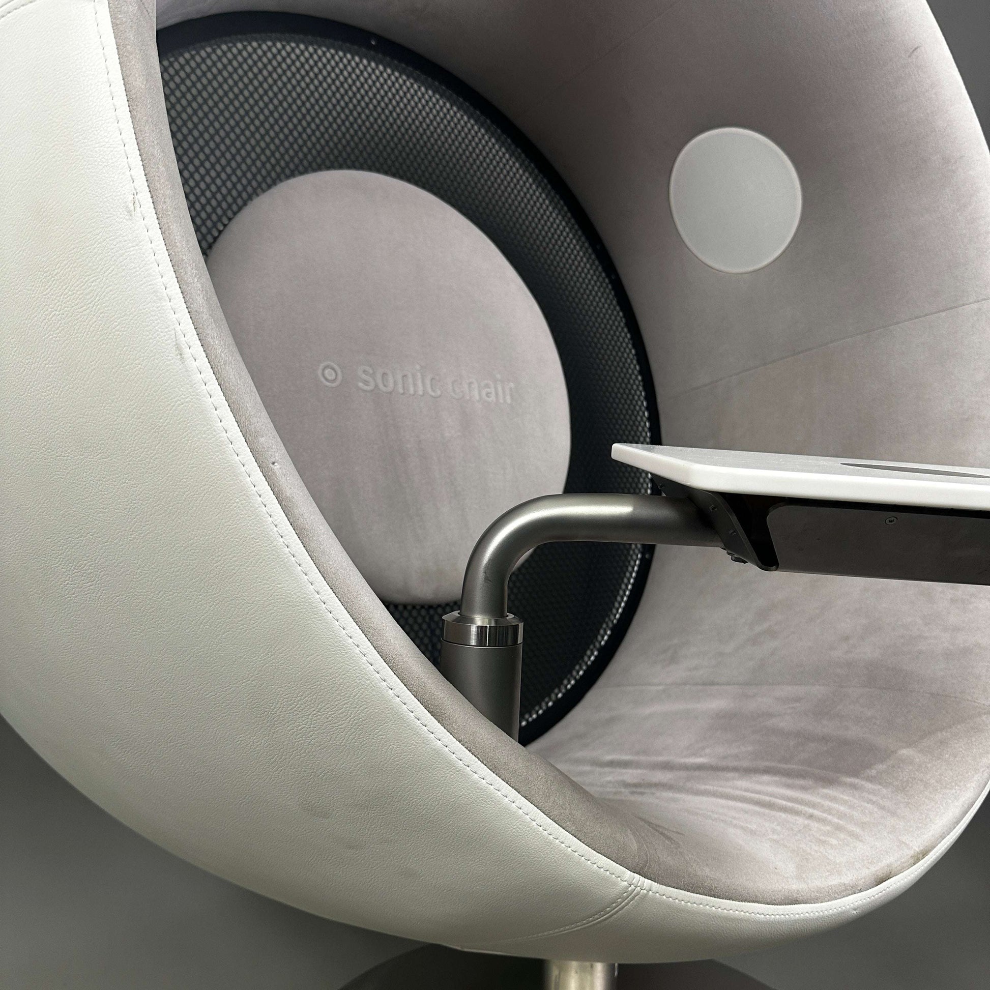 Sonic Chair 3.1 Audiosessel aus weißem Glattleder mit hellgrauem Veloursleder, integrierter Laptoptisch und hochwertiger Körperschallmembran für intensives Klangerlebnis.