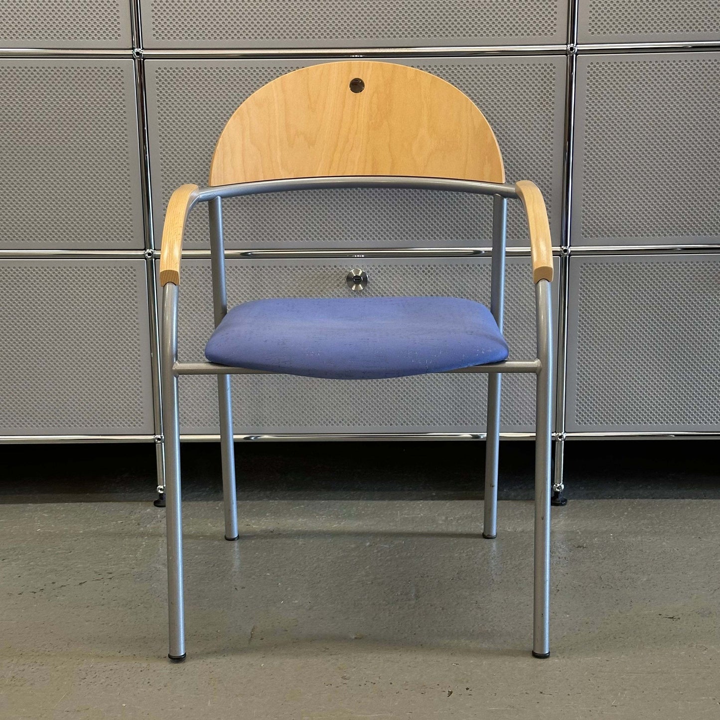 Stackable chair with beech wood backrest, blue fabric seat, and silver metal frame.