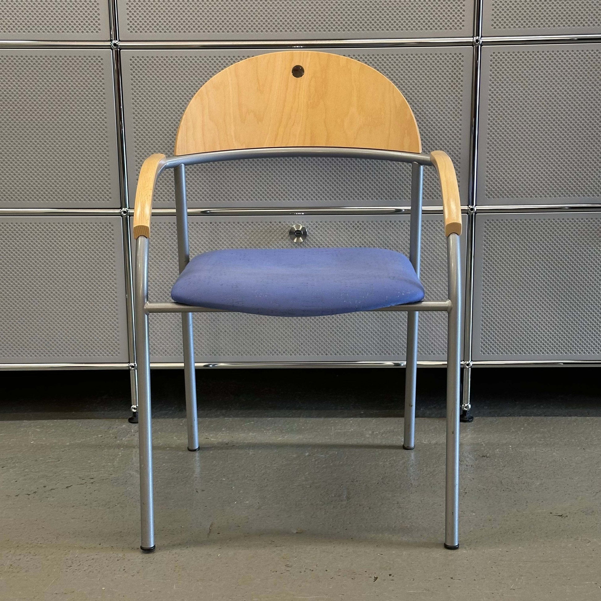 Stackable chair with beech wood backrest, blue fabric seat, and silver metal frame.