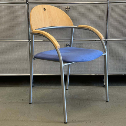 Stackable chair with beech wood backrest, blue fabric seat, and silver metal frame details