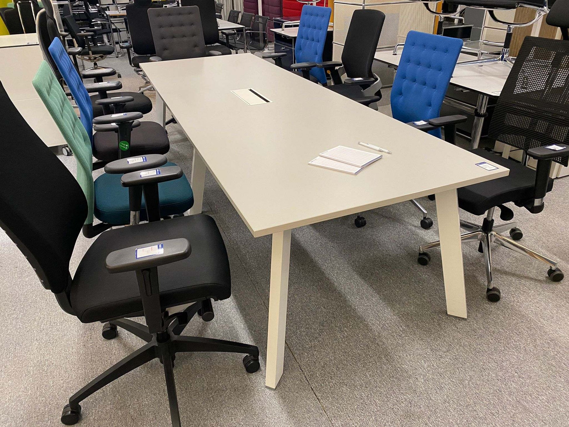 Steelcase Konferenztisch with light grey top and white metal legs, 300cm by 100cm, surrounded by office chairs in a showroom.