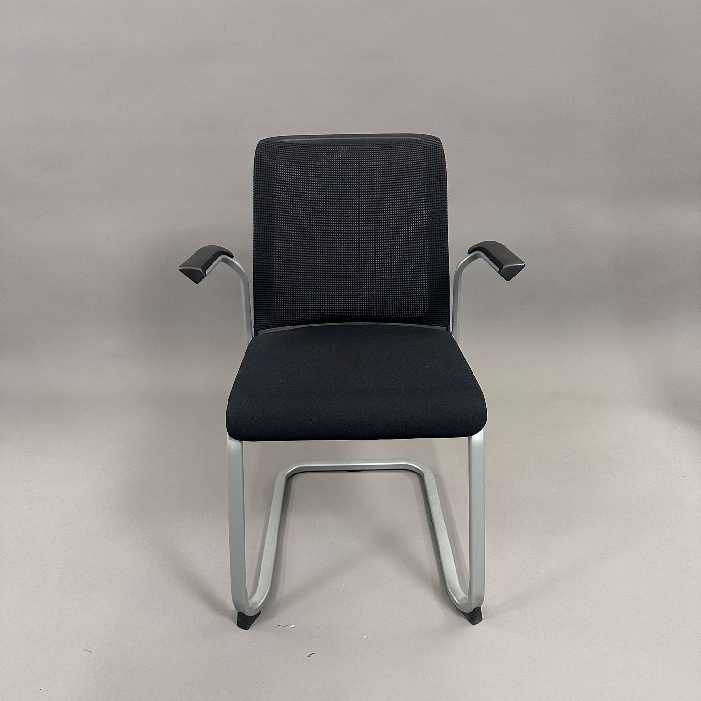 Steelcase Northside black mesh back meeting chair with silver frame and armrests, stackable design.