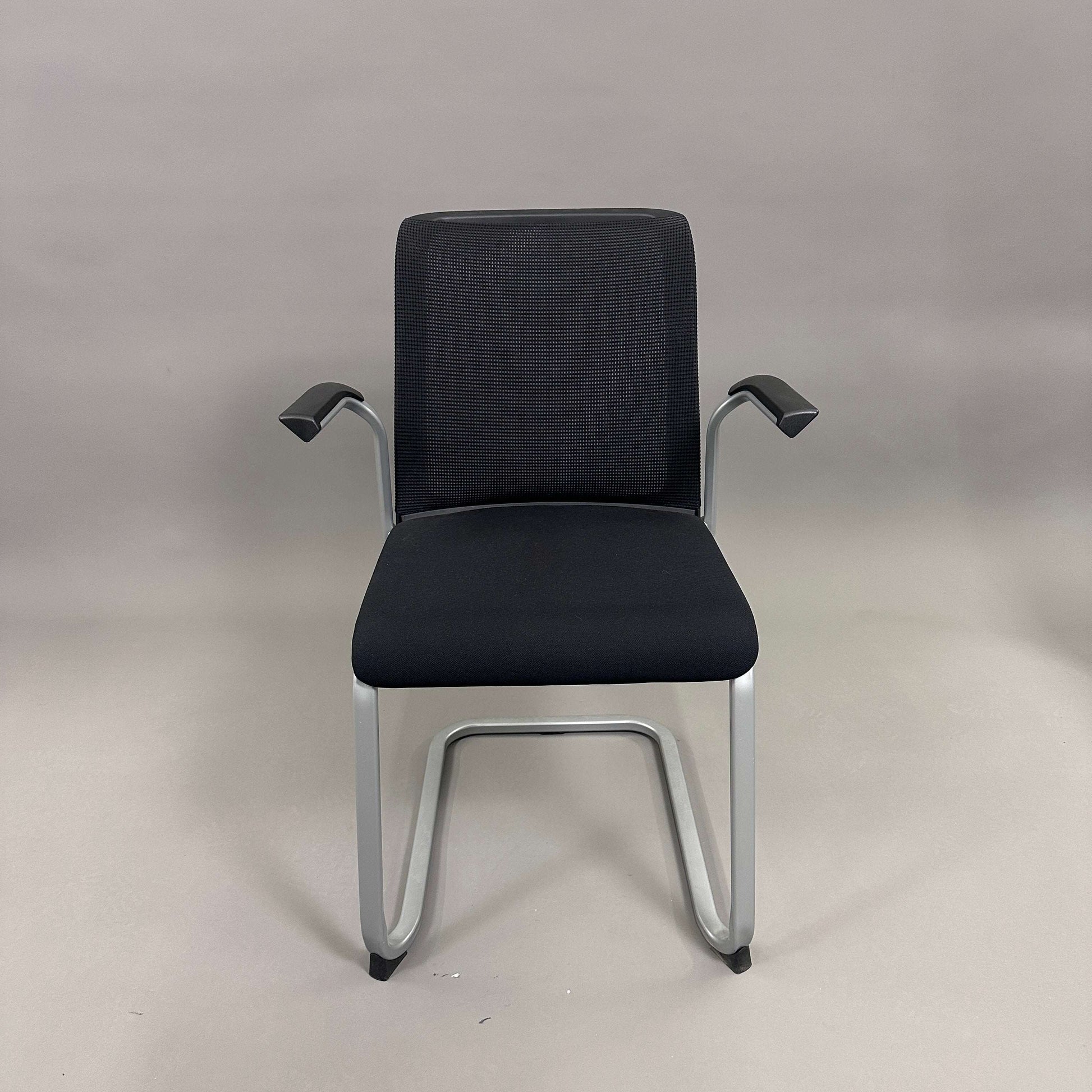 Steelcase Northside black mesh back meeting chair with silver frame and armrests, stackable design.