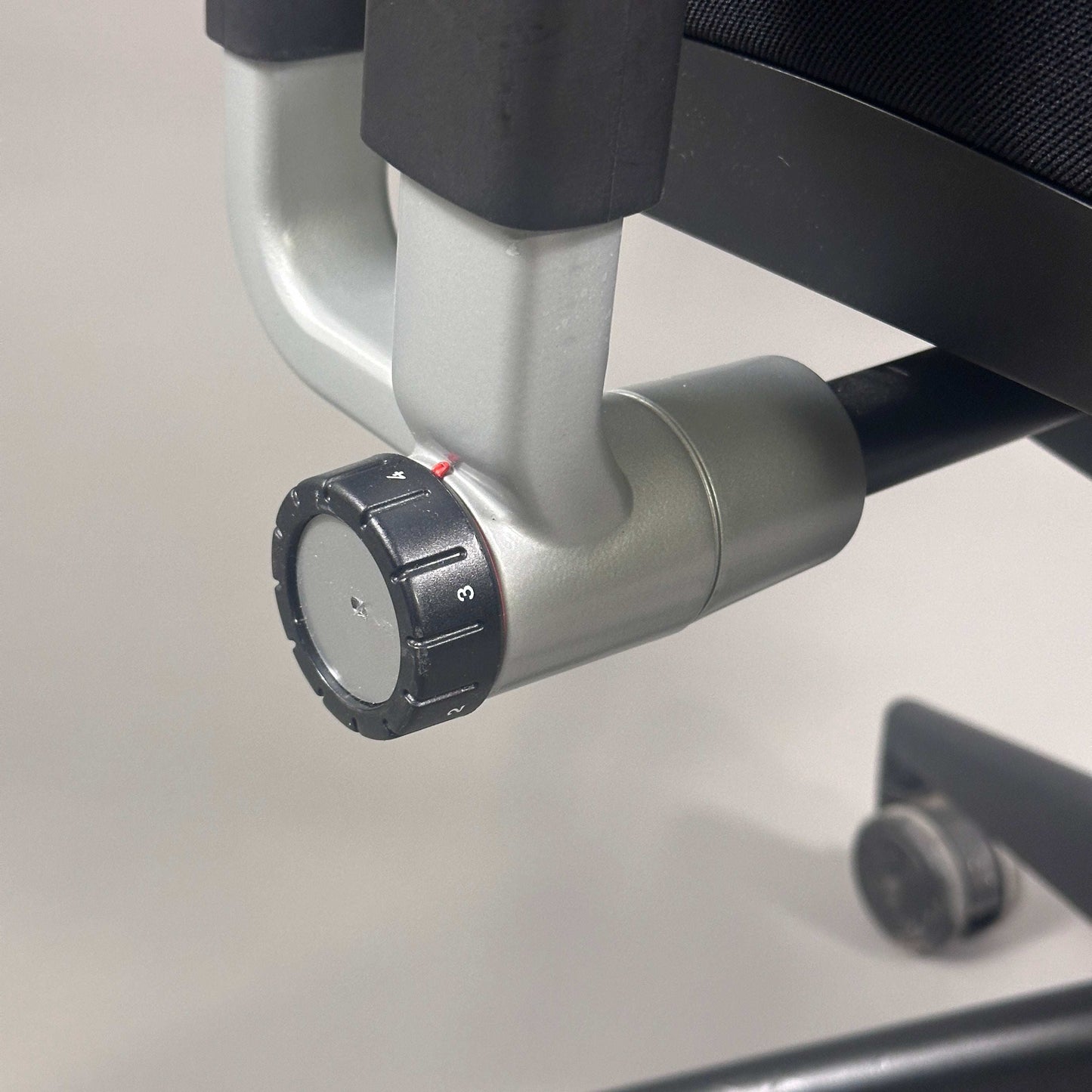Detailaufnahme des verstellbaren Rückenkraft-Drehknopfs eines schwarzen Steelcase Please Bürostuhls