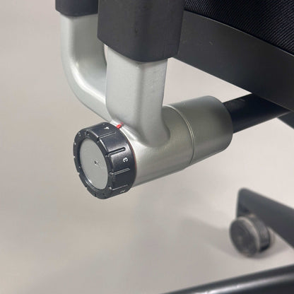 Detailaufnahme des verstellbaren Rückenkraft-Drehknopfs eines schwarzen Steelcase Please Bürostuhls