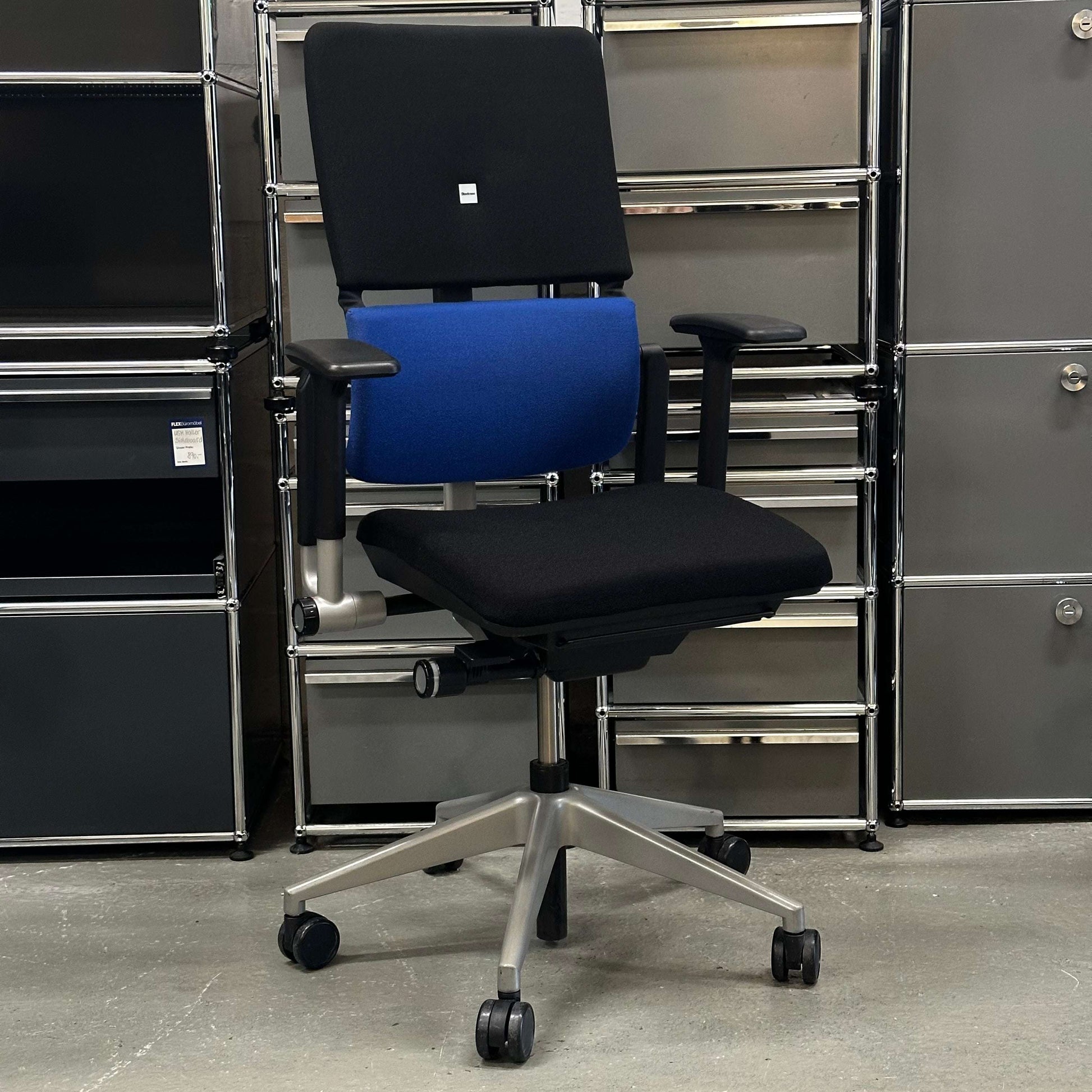 Steelcase Please ergonomic office chair with blue lumbar support and black seat in modern workspace