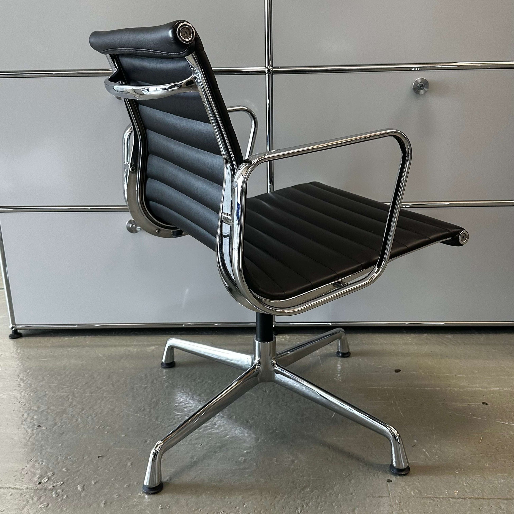 Black Vitra EA108 style office chair replica with chrome frame and leatherette upholstery