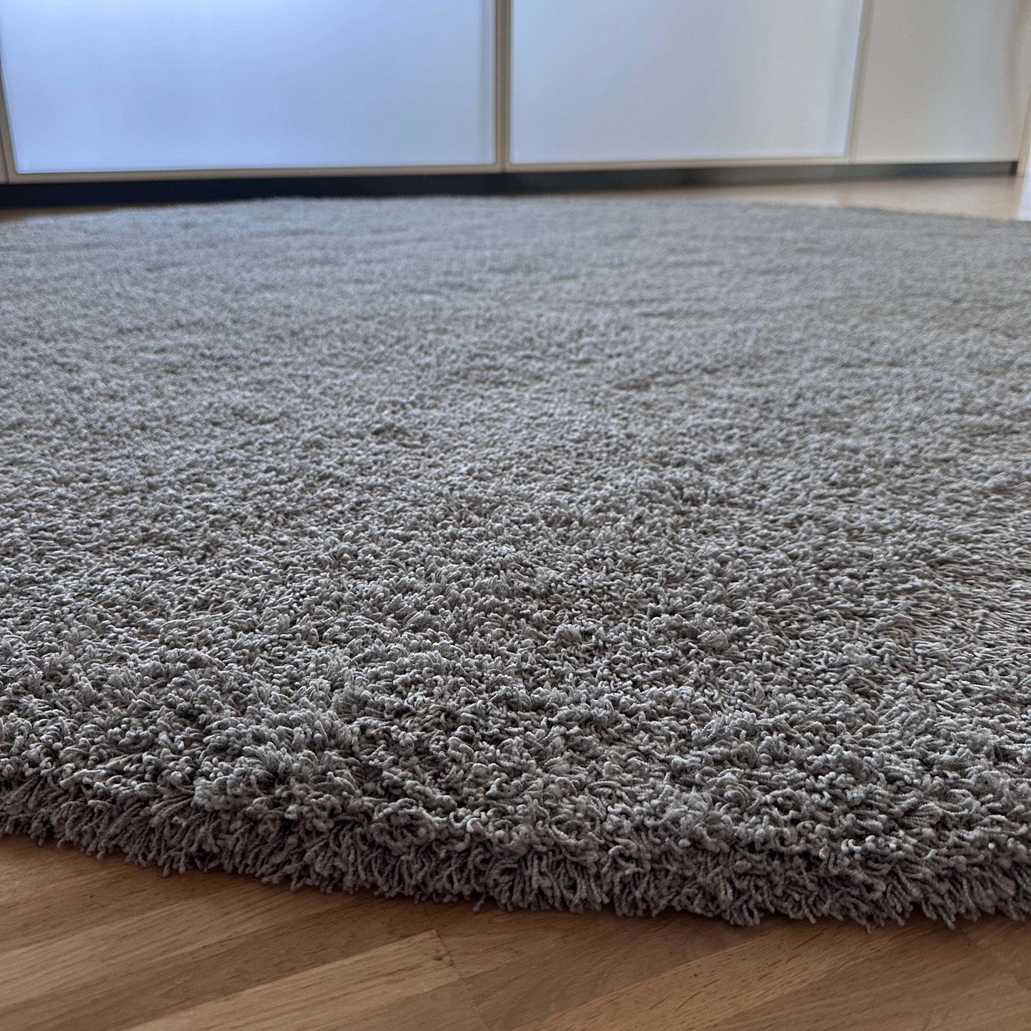 Round anthracite Object Carpet RugX with low pile texture on wooden floor