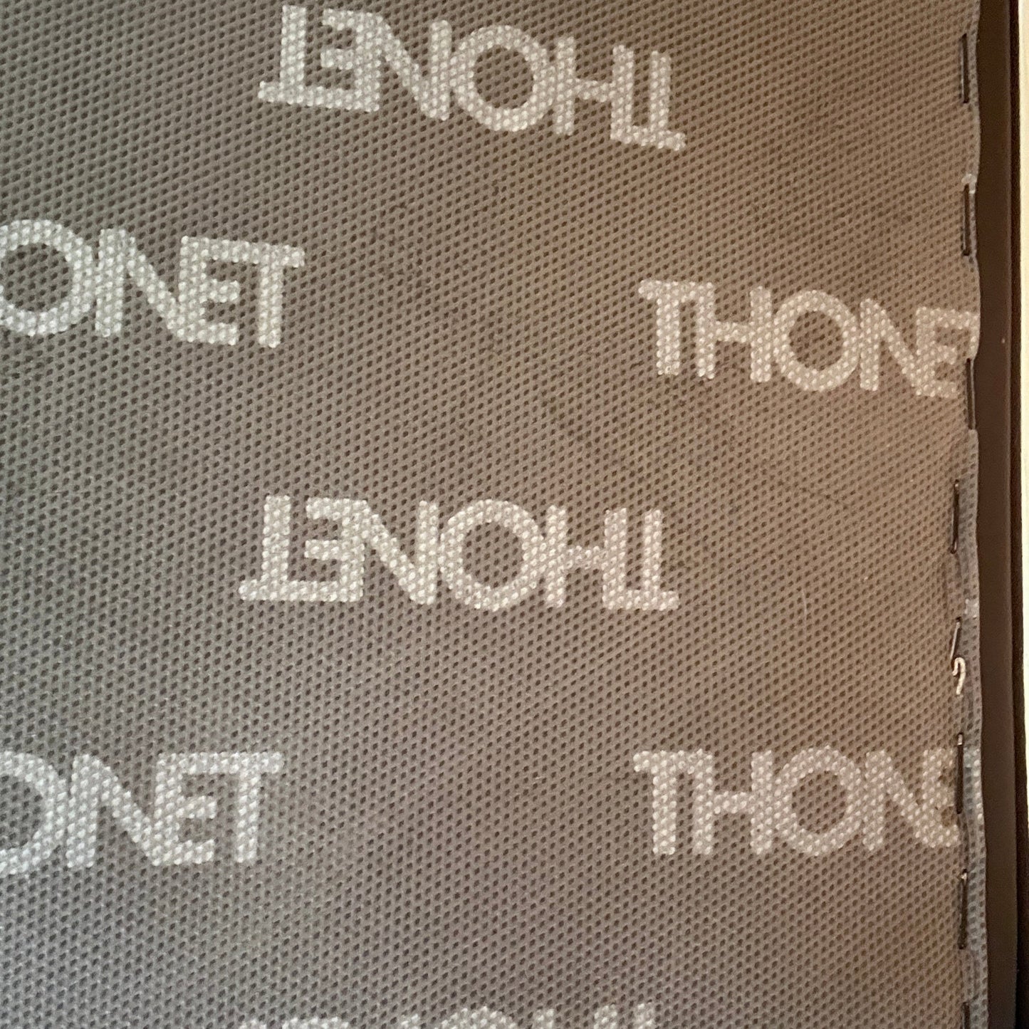 Thonet S 411 Freischwinger Sessel mit schwarzem Lederpolster und Thonet-Logo-Muster.