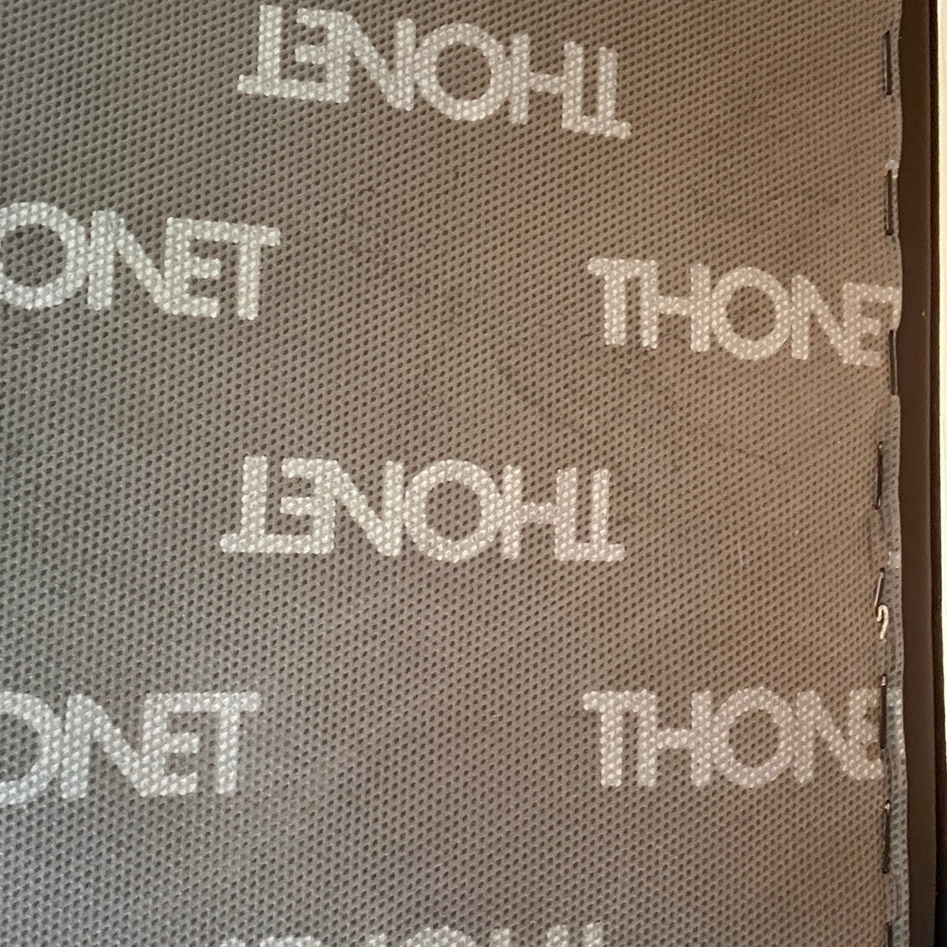 Thonet S 411 Freischwinger Sessel mit schwarzem Lederpolster und Thonet-Logo-Muster.