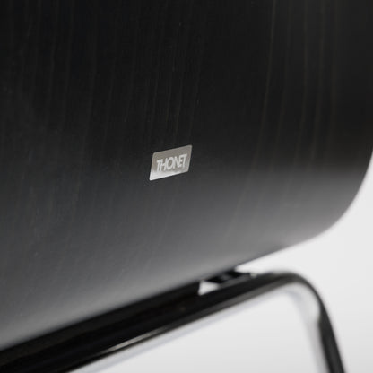 Close-up of a black Thonet S166 PF chair, showing the Thonet logo on the dark wood backrest.