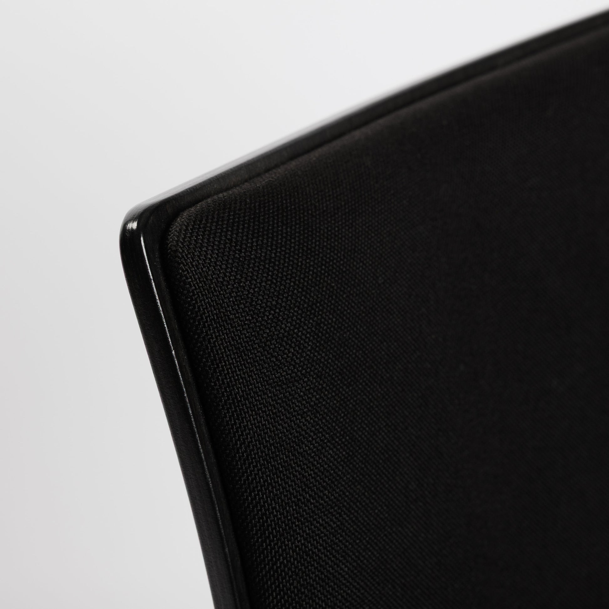 Detailaufnahme des schwarzen Thonet S166 PF Stuhls mit Stoffpolsterung und glänzender Holzkante.