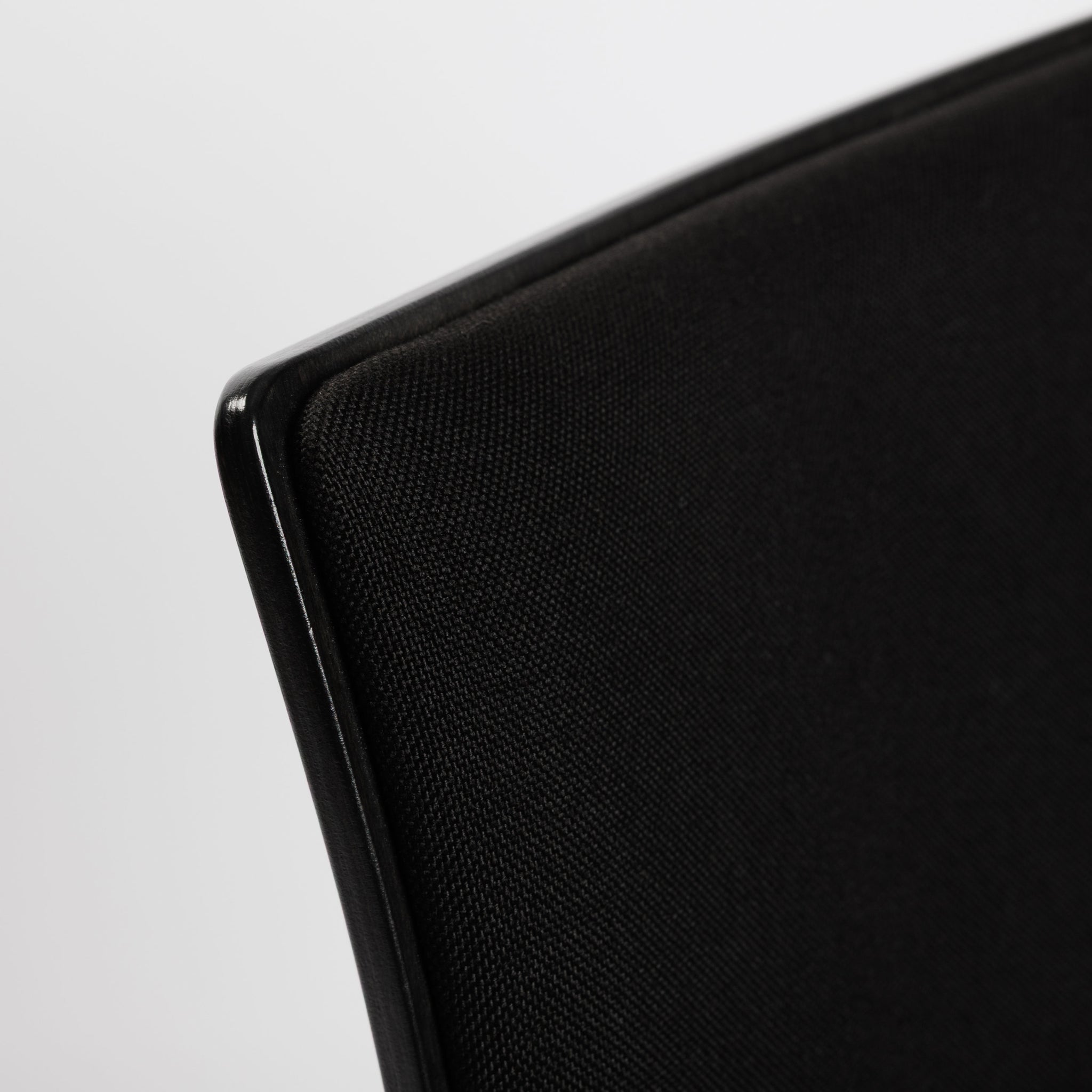 Detailaufnahme des schwarzen Thonet S166 PF Stuhls mit Stoffpolsterung und glänzender Holzkante.
