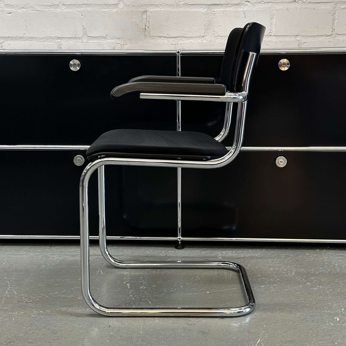 Thonet S43 PVF black chair with chrome frame, wooden armrests, and fabric upholstery, side view