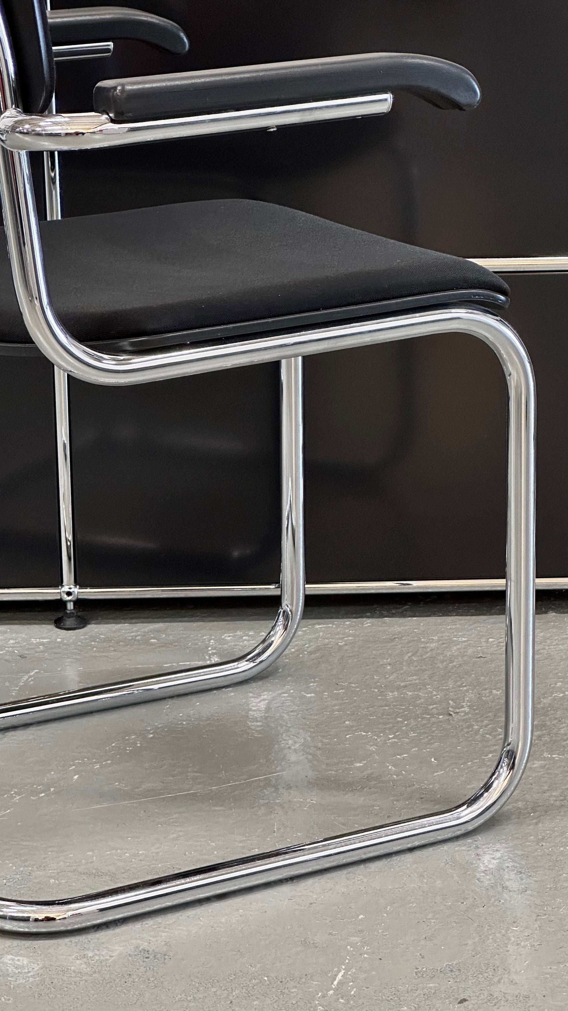 Thonet S43 PVF chair with chrome frame, black fabric seat, and wooden armrest in modern design